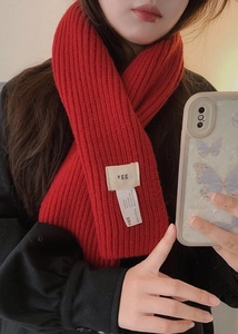 Détail de l'étiquette de l'écharpe en maille rouge montrant la composition en laine
