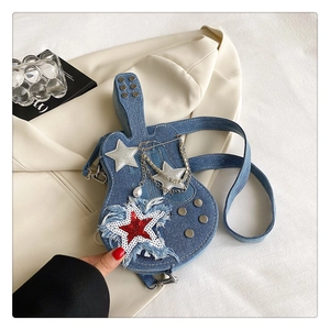 Dettaglio borsa a chitarra in denim blu con stelle d'argento e catene decorative