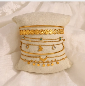 Detailed view of bohemian gold layered bracelets with butterfly and moon charms on a pillow