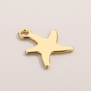 Polished gold starfish pendant charm for DIY jewelry making on a beige background
