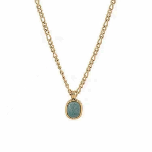 Macro shot of gold Figaro chain with oval turquoise stone pendant on white background