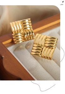 Detail of gold-plated square stud earrings with cross-woven texture on velvet