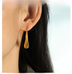 Detailed close-up of golden teardrop earrings on model showing elegant polished finish
