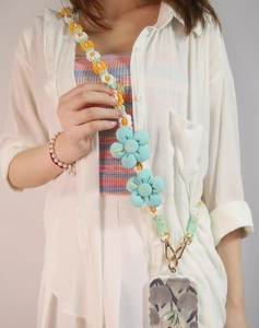 Detail of hand-woven crossbody phone strap with yellow-white daisies and blue smiley flowers