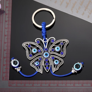 Vintage evil eye butterfly keychain with blue beads and silver frame on black background