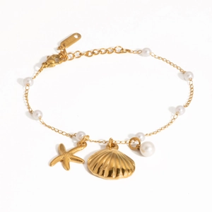 Detailed view of gold starfish and shell charms with white pearls on a steel bracelet