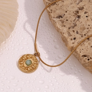 Macro detail of 18K gold snake chain necklace with hammered coin eye pendant and amazonite