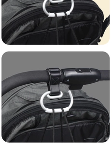 Detail of a large white aluminum carabiner hook with leather strap on a stroller handlebar