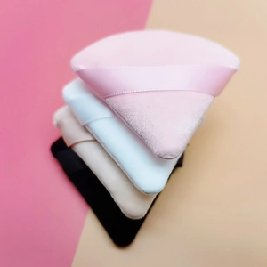 Detailed view of four colorful triangular velvet makeup puffs with matching silk ribbons