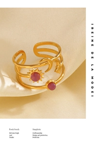 Detail of gold open ring with celestial motifs, pink gemstones, and silk background