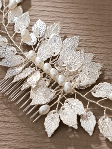 Macro detail of silver leaf hair comb with white pearls on a wooden background