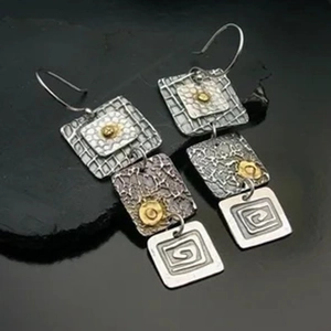 Detail view of vintage tribal geometric earrings with etched spiral motifs and hammered metal