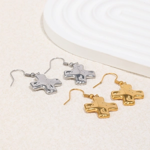 Détail de boucles d'oreilles croix en or et argent avec surface martelée à effet de lave