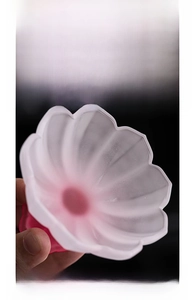 Close-up of a lotus-shaped frosted glass tea cup with pink gradient and petal detail