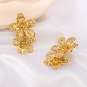 Elegant gold flower earrings with a brushed metal texture on white silk background