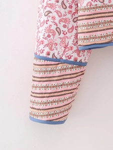 Close-up of quilted floral sleeve cuffs and striped hem details with blue piping
