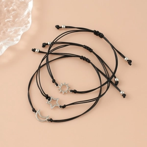 Detail of adjustable black cord bracelets with silver sun moon and star charms