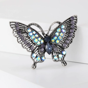 Vintage silver butterfly brooch with blue and purple rhinestones on white stairs
