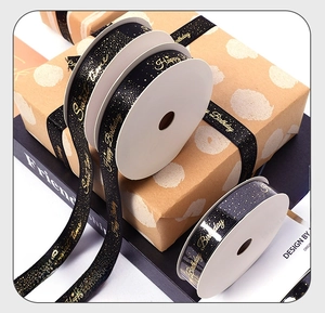 Detail of black satin Happy Birthday ribbon with gold foil lettering for gift wrapping