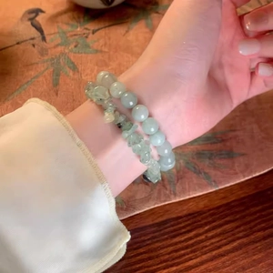 Close-up of stacked jade beads and irregular crystal bracelets on a vintage table