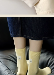 Detailed knit texture and Skaimim fabric label on yellow cotton crew socks for women