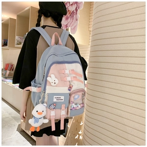 Detail of blue and pink school backpack featuring multiple compartments and soft charms