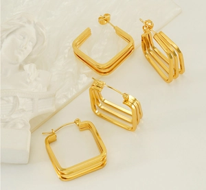Detail of layered gold geometric square earrings with high-polish metallic finish