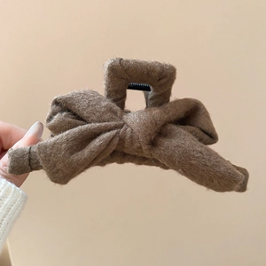 Detail of brown plush bow hair claw clip showing soft fabric texture and warm autumn style