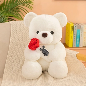 Peluche de osito blanco con rosa roja y lazo de lunares sobre una manta de punto suave