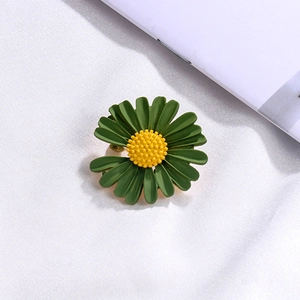 Macro shot of dark green enamel daisy brooch with a textured yellow core detail