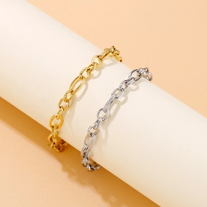 Golden and silver stainless steel chunky link bracelets set on white cylindrical stand