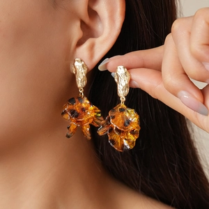 Detail shot of vintage acrylic petal tassel earrings with amber resin and gold metal