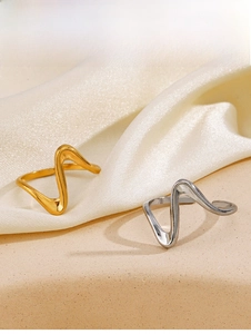 Close-up of gold and silver wavy irregular open rings on elegant silk fabric background