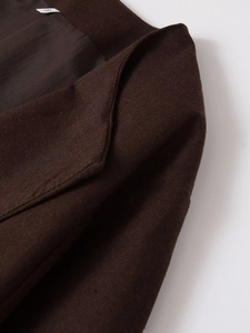 Detail van de donkerbruine blazer kraag en schouder met woltextuur en maat S label