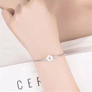 Silver open cherry blossom bracelet with white floral pendant on woman's wrist