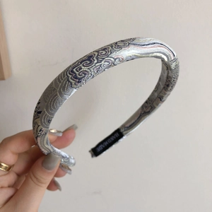 Dettaglio del cerchietto in tessuto jacquard grigio e argento con etichetta handmade