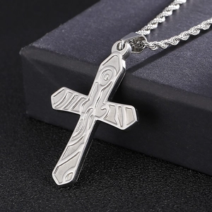 Macro shot of silver titanium steel cross pendant with detailed textured engraving