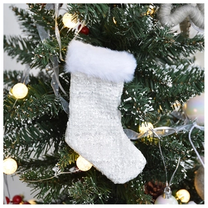 Close-up of tweed Christmas stocking ornament hanging on a festive tree with warm lights