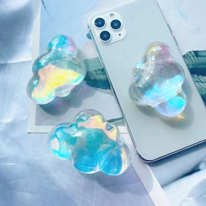 Close-up of three transparent holographic cloud-shaped pop-up phone grips on fabric