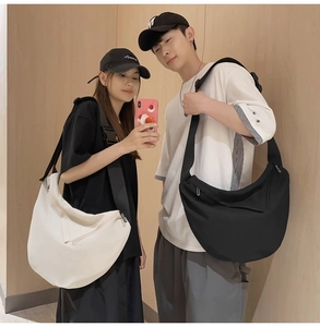 Detail showing high-capacity half-moon crossbody bags in black and white canvas on models