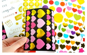 Close-up of decorative gold and pink heart stickers with various greeting patterns