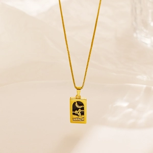 Macro detail of gold tarot pendant featuring moon and star zircon inlay on box chain