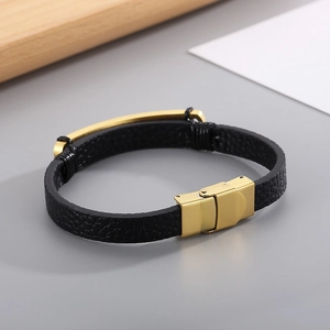 Detail eines schwarzen Lederarmbands mit goldenem Magnetverschluss und polierter Platte