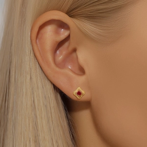 Close-up of gold s925 silver stud earring with square red zircon and filigree detail