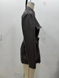 Détail d'une veste longue en similicuir marron foncé avec ceinture et boutons dorés