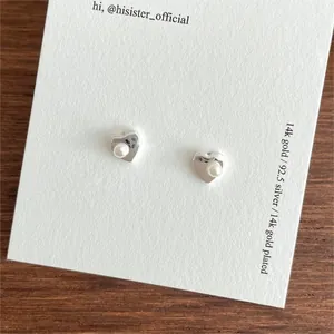 Detail of 925 sterling silver heart earrings with 14k gold plating and white pearls