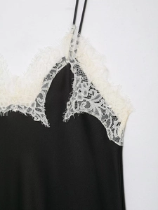 Détail d'un caraco en satin noir avec bordure en dentelle blanche raffinée au décolleté