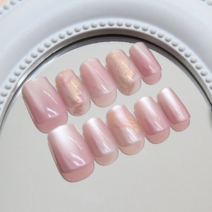 Pink cat eye press-on nails with marble design and gold foil on a mirror tray