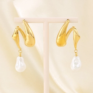 Detail of gold twisted metal earrings with white baroque pearl pendants on silk