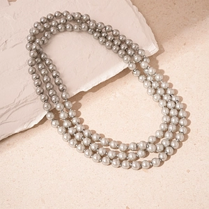 Close-up of three-layer gray pearl necklace with metallic luster on stone base